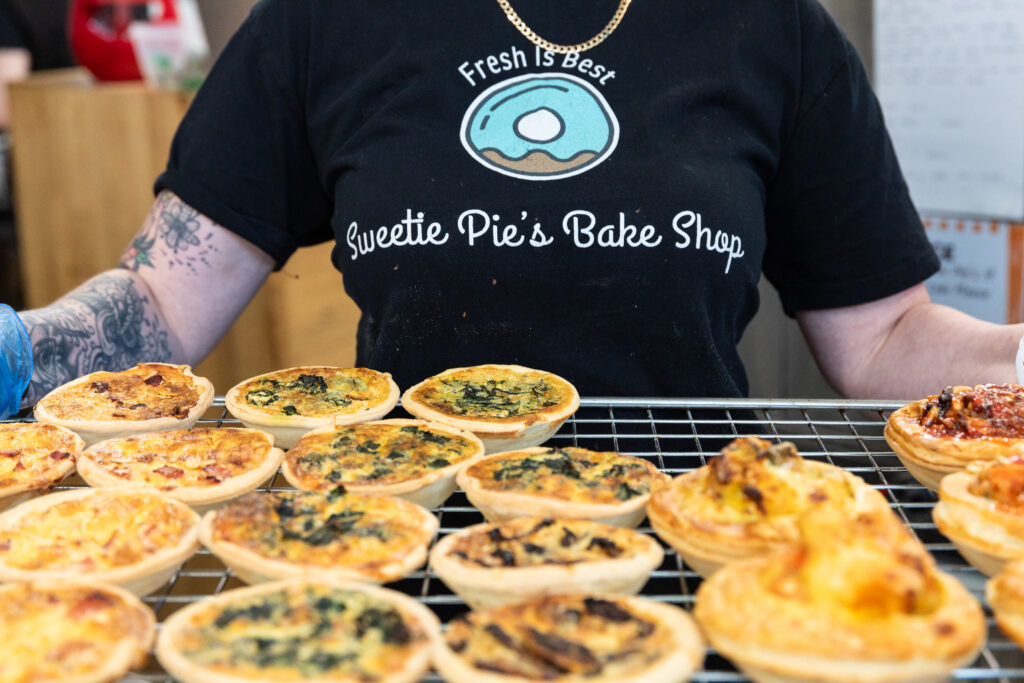 Staff member holding a tray of pies and quiches