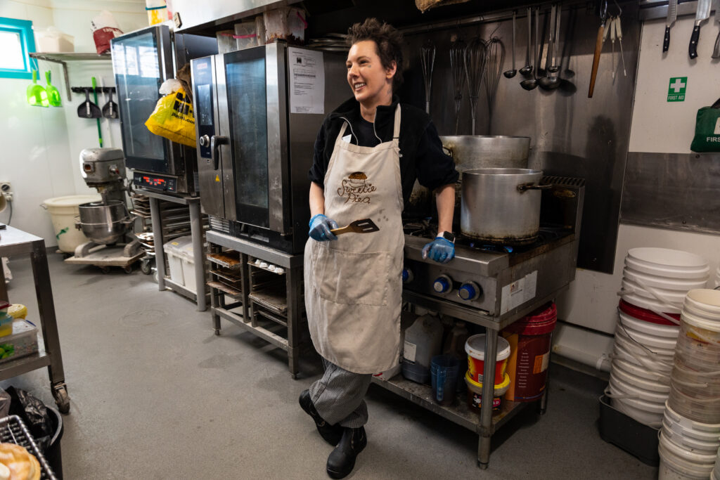 Nicole Hyde in the bakery wearing a Sweetie Pies apron and smiling.